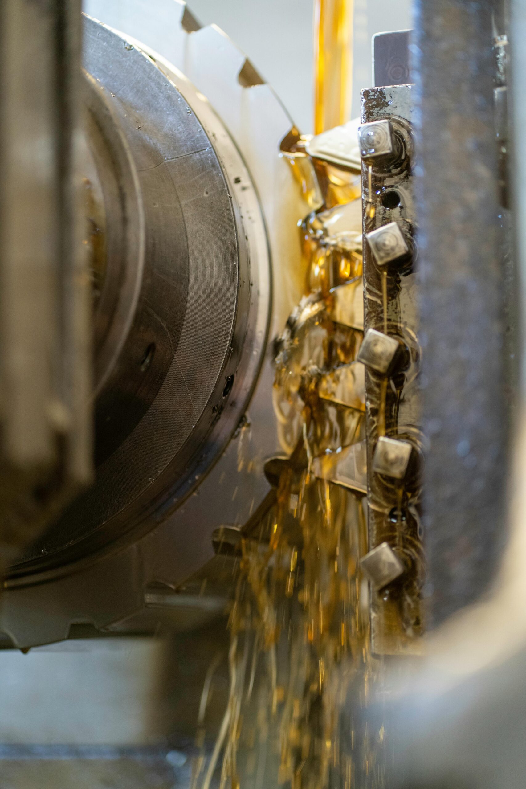 Detailed view of metal cutting in an industrial machine with oil lubrication.